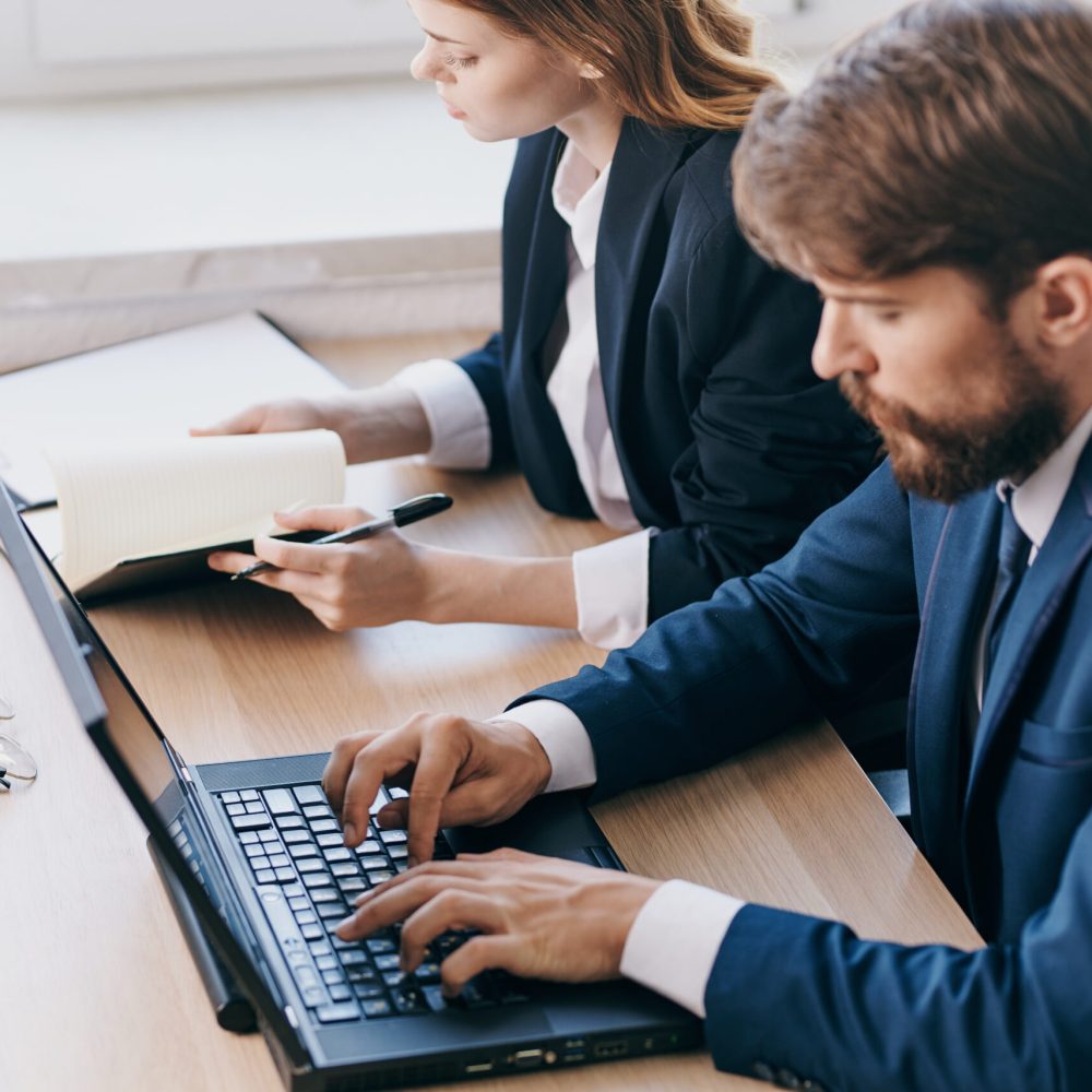 business man and woman sitting at a desk with a laptop communication finance technologies. High quality photo